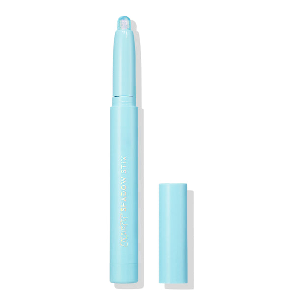 Colourpop Game Over Shadow Stix with shimmering icy blue cream eyeshadow bullet exposed, standing upright with cap off beside it on a clean white background for a minimalist product display.