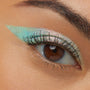 Close-up of a brown eye wearing Colourpop Game Over Shadow Stix, showcasing a sharp, winged swipe of shimmery mint-green and pink duochrome eyeshadow across the upper lid for a bold, metallic finish.