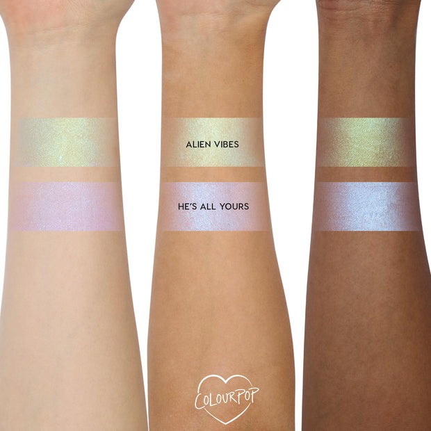 ColourPop Shadow Stix Cute and Feisty swatched on three arms - two bands per arm labeled Alien Vibes (gold‑green shimmer) and He’s All Yours (pink‑lilac blue shift) - showing creamy payoff across light, medium, and deep skin tones.