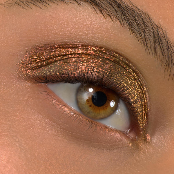 Copper‑bronze metallic eyeshadow sweeps across the lid in a macro close‑up, highlighting natural lashes and crease detail; Love Triangle shade applied with ColourPop Shadow Stix for creamy, long‑wear shimmer.