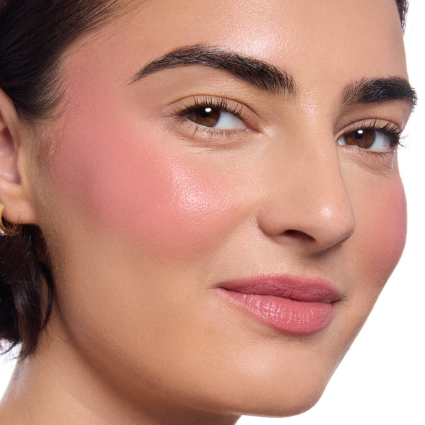 Model’s cheeks and lips wearing True Love’s Form ColourPop Lip and Cheek Balm, delivering a dewy medium pink flush on cheeks and a soft rose tint on lips, captured in a tight studio close-up against a clean white background.