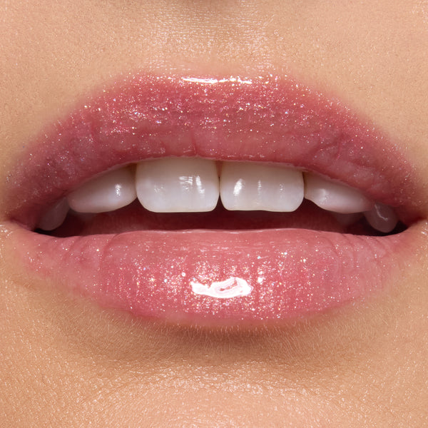 Glossy lips wearing ColourPop Ultra Glossy Lip in Totally Swamped, a sheer pink shimmer with fine sparkle, reflecting high shine in a studio close-up to showcase the smooth, hydrated finish.