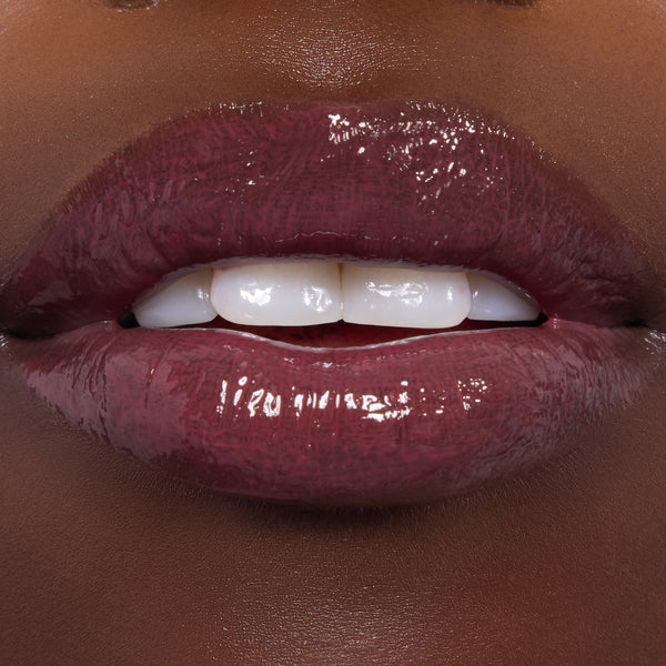 Glossed lips showcase ColourPop Ultra Glossy Lip in Short Lord, a deep berry‑plum shade with glassy, full‑coverage shine, applied evenly on smooth lips; tight macro shot highlighting the reflective finish for a product swatch.