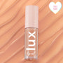 ColourPop Lux Lip Oil Skinny Dip tube resting on glossy peach swirls, showcasing a clear bottle with vertical 'lux' logo and pale pink cap with star motifs, plus a heart 'Cult Fave' badge in the corner.