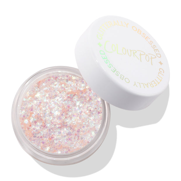 Open round pot shows iridescent opal flakes suspended in peachy-clear gel - ColourPop Glitter Gel, So Cute - while the white screw-top lid printed “Glitterally Obsessed” rests ajar on a clean white background.