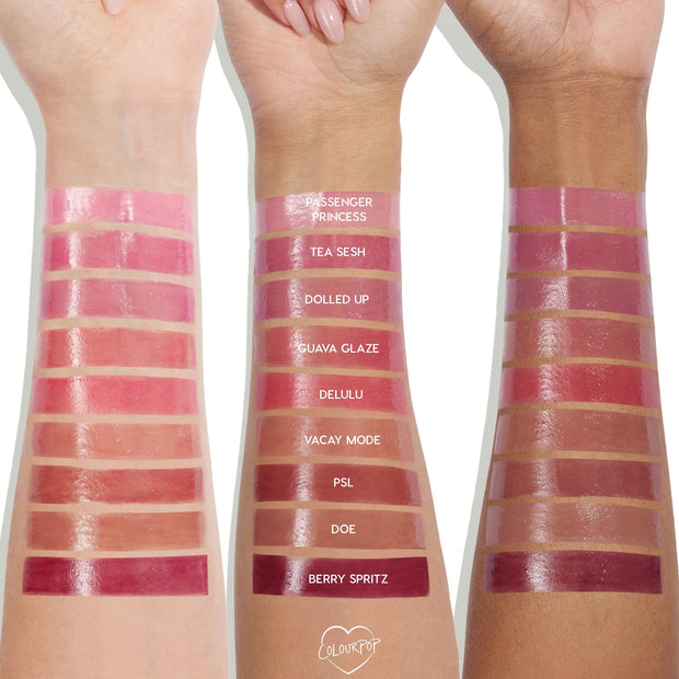 Guava Glaze swatched on three forearms, a sheer warm pink with a glossy, plumping shine from ColourPop So Juicy Plumping Gloss Balm with Peptides, shown alongside labeled shades like Passenger Princess and Berry Spritz for cross‑tone comparison.