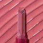 Heart-shaped tip of the Forbidden Love shade glides across a ribbed, glossy rose‑pink swatch, highlighting the shine and creamy payoff of the ColourPop So Juicy Plumping Gloss stick in a clear pink tube.