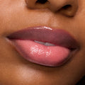 Glossed lips subtly parted, showcasing Forbidden Love, a rosy pink shade of the ColourPop So Juicy Plumping Gloss, delivering a plumped, high-shine wet look in a close-up studio beauty shot.
