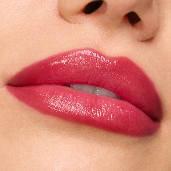 Glossed lips wearing ColourPop So Juicy Plumping Gloss in Spice Level, showing a high-shine, plumped, rosy-red tint; macro close-up emphasizes smooth texture, even coverage, and juicy hydration.