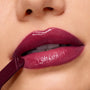 Berry-toned lips wear ColourPop So Juicy Plumping Gloss in Temptation, the heart-tipped applicator gliding on a high-shine, cushy finish; tight macro studio shot highlighting the smooth, plumped look and rich pigment.