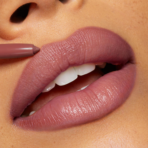 ColourPop Group Chat So Juicy Plumping Lip Liner with Peptides lining full lips in a mauve‑nude shade, pencil tip defining the cupid’s bow for a smooth, glossy, fuller look in a tight close-up.