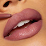 ColourPop Group Chat So Juicy Plumping Lip Liner with Peptides lining full lips in a mauve‑nude shade, pencil tip defining the cupid’s bow for a smooth, glossy, fuller look in a tight close-up.
