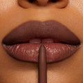 Close-up lip liner pencil defining glossy, full lips in a rich mocha-brown; precise application of ColourPop So Juicy Plumping Lip Liner with Peptides, Mocha Latte, creating smooth, contoured edges and a plumped finish.