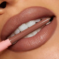 ColourPop So Juicy Plumping Lip Liner with Peptides in Tease defining full lips as the nude-brown pencil, with a blush-pink cap, is held between teeth, showcasing precise, creamy payoff and smooth contour in a studio close-up.