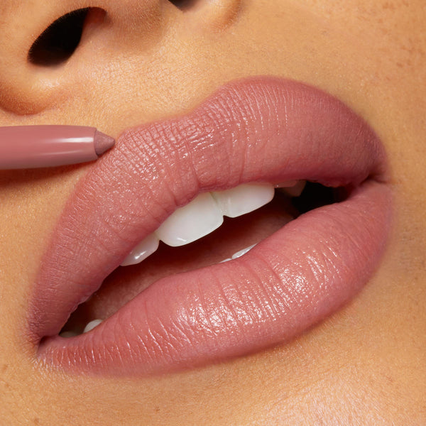 Westwood lip liner defining full lips as the ColourPop So Juicy Plumping Lip Liner with Peptides glides on in a soft rosy-mauve hue, outlining and enhancing a smooth, hydrated finish in a tight beauty close-up.