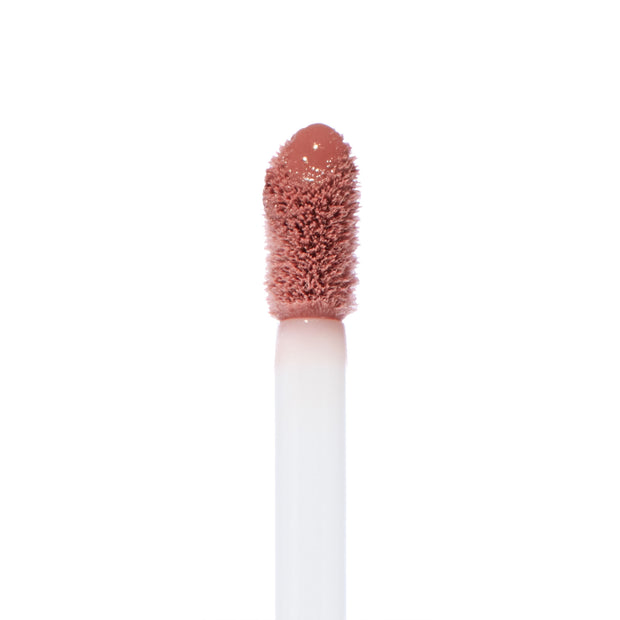 Doe-foot applicator coated in rosy nude shade Still an Icon glistens in a macro close-up, showcasing the soft-blur, semi-matte texture of the ColourPop Ultra Blotted Lip against a clean white background.