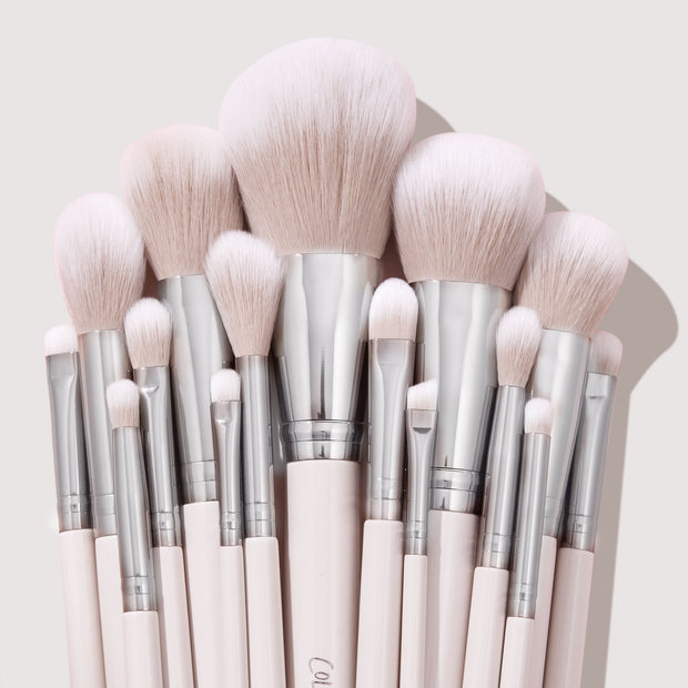 Stone Cold ColourPop Makeup Brush Kit fanned upright, displaying powder, blush, contour, and eye brushes with fluffy blush-pink bristles, silver ferrules, and pale pink handles, stacked tightly against a soft beige backdrop.