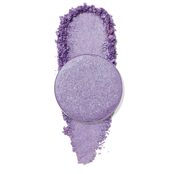 Round pan of ColourPop Pressed Powder Shadow, Subdue, a shimmery lavender-purple eyeshadow shown swatched and slightly crushed with sparkly microglitter on a clean white background.