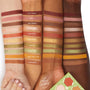 Sweet As Can Bee ColourPop Shadow Palette swatched in clean stripes on three arms from light to deep skin tones, showing matte and metallic hues from honey gold and rust to olive green and pink; shade names labeled on a white studio backdrop with palette corner visible.