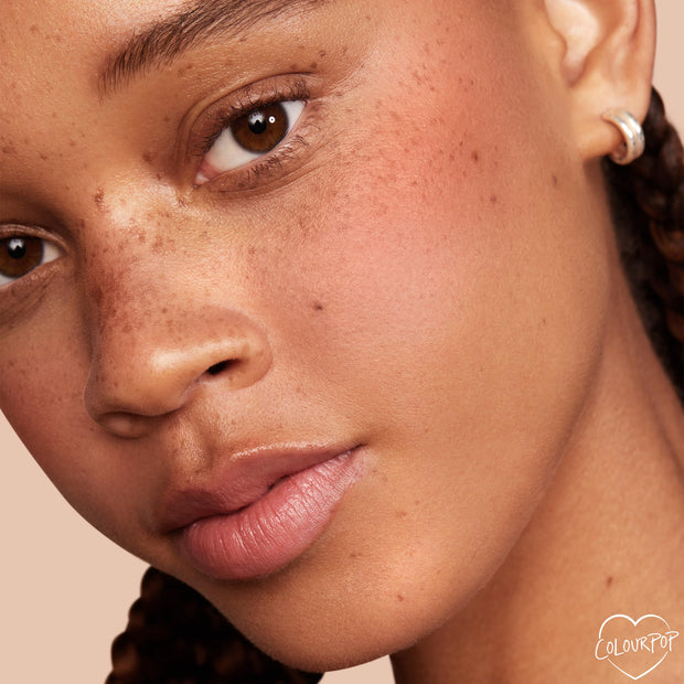 ColourPop Pretty Fresh Tinted Moisturizer in Medium 12 W perfecting a freckled complexion, delivering a dewy, even, skin-like finish on a close-up face against a soft peach background, ideal for everyday lightweight coverage.
