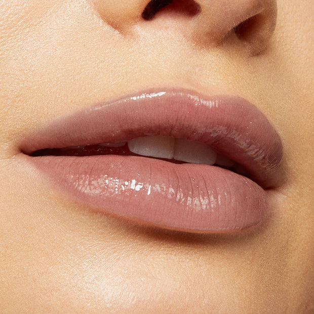 Glossy nude‑pink lips wearing Team Jacob, a ColourPop Lux Lip Oil, showcasing a high‑shine, sheer finish and smooth texture in a tight beauty close‑up.