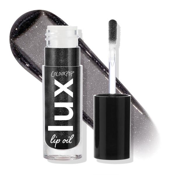 Team Jacob ColourPop Lux Lip Oil displayed open, doe-foot applicator beside the tube and a glossy charcoal-black swatch with silver shimmer behind, highlighting the sheer, high-shine finish; cap off on a white studio backdrop.