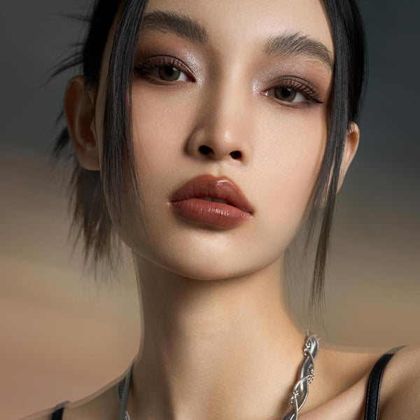 That’s Taupe ColourPop Shadow Palette creating a cool‑taupe smoky eye on a model - soft matte crease, silver‑taupe shimmer lids, and defined liner - paired with nude glossy lips in a tight beauty close‑up against a neutral studio backdrop.