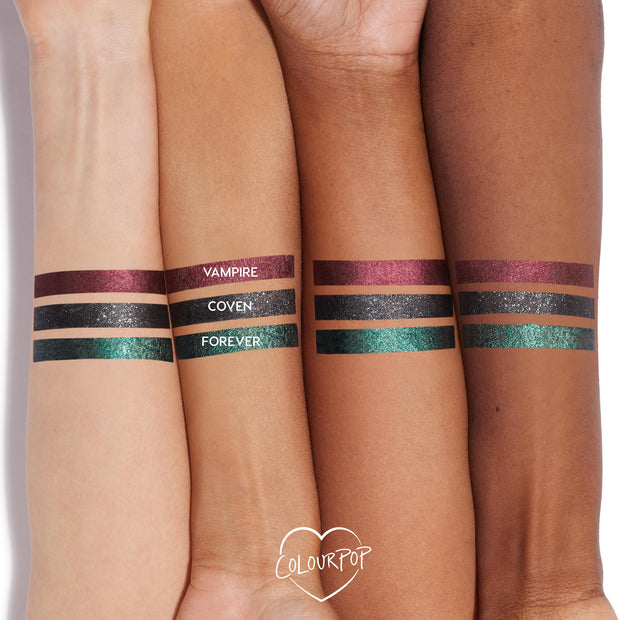 ColourPop Graphix Ink Liner “I Know What You Are” swatched on three arms: metallic burgundy Vampire, black‑silver sparkle Coven, and emerald‑teal shimmer Forever, shown in neat stripes across light to deep skin tones in a studio close‑up.