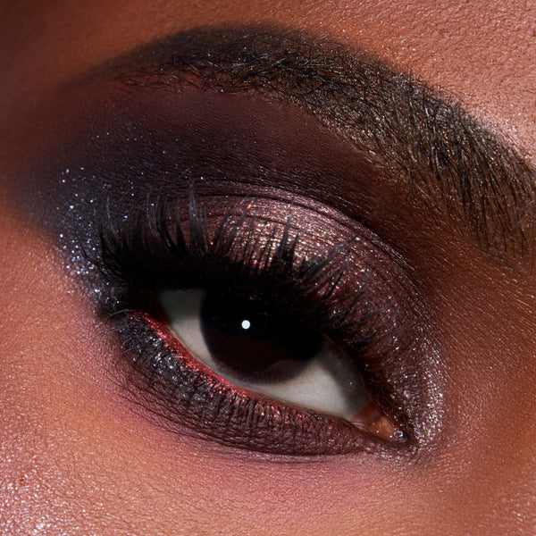 Close-up eye wearing the Eternal Eclipse Eye Trio, showcasing shimmery Twilight-inspired smokey plum and charcoal shadow with metallic sparkle on the lid and lower lash line for a dramatic evening makeup look.