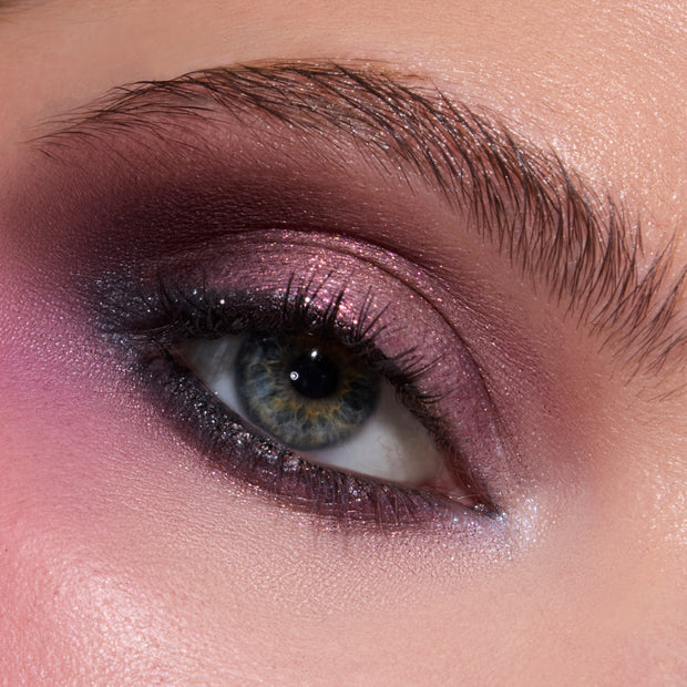 Close-up of a model’s eye wearing the Eternal Eclipse Eye Trio, showcasing shimmer plum and mauve Twilight-inspired eyeshadow blended along the lid and lower lash line for a dramatic, smokey metallic finish.