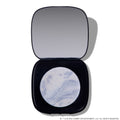Open compact of Change Me Mega Highlighter with shimmering icy lavender and silver marbled pan set in a sleek black case with mirror, styled on a white background for the Twilight makeup collection.