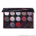 Eclipse shadow palette from the Twilight collection lying open, showing 15 circular pans of matte and glitter eyeshadows in silvers, reds, purples, and deep neutrals arranged in three rows inside a black and red themed case.