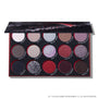 Eclipse shadow palette from the Twilight collection lying open, showing 15 circular pans of matte and glitter eyeshadows in silvers, reds, purples, and deep neutrals arranged in three rows inside a black and red themed case.