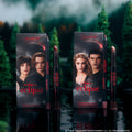 ColourPop Twilight Immortal Kiss Lippie Stix Duo stands upright on a reflective lake surface, with Eclipse-themed character boxes and matching deep nude and berry lip pencils and sticks framed by a dark, misty forest backdrop.