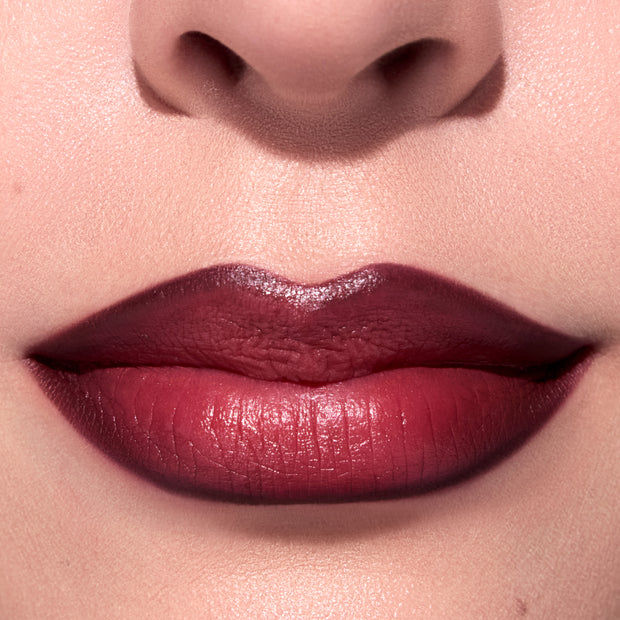 Close-up of a model’s lips wearing ColourPop New Love Lippie Stix, showing a rich Twilight-inspired deep berry red lipstick with a smooth satin finish and softly blurred edges against fair, flawless skin.