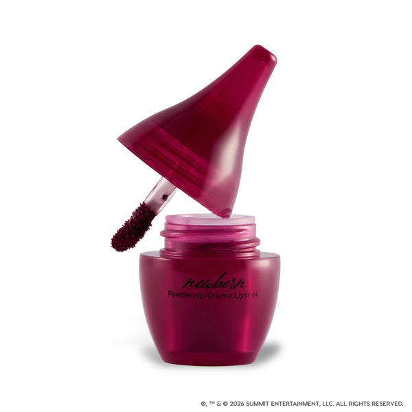 Newborn Powder to Creme Lipstick from the Twilight collection shown open on a white background, with a deep berry doe-foot applicator emerging from a glossy burgundy jar featuring sleek black branding.