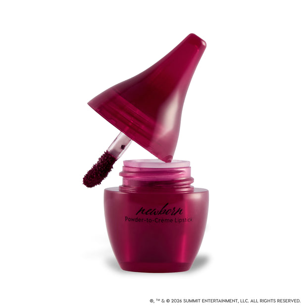 Newborn Powder to Creme Lipstick from the Twilight collection shown open on a white background, with a deep berry doe-foot applicator emerging from a glossy burgundy jar featuring sleek black branding.