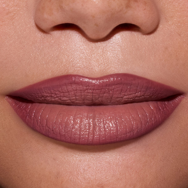 Close-up of full lips wearing ColourPop Opposites Attract Lippie Stix, showing a smooth, satin-matte mauve finish inspired by Twilight tones on medium skin, highlighting even coverage and creamy texture for everyday makeup looks.