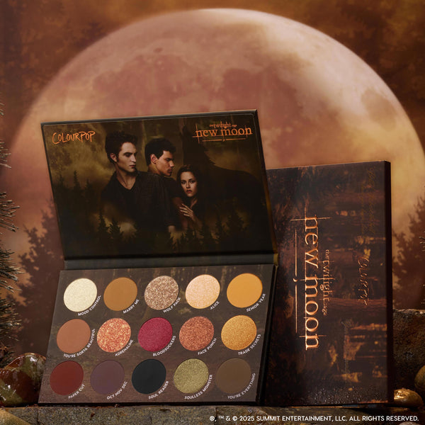 ColourPop Twilight Forever palette trio New Moon edition opened to show 15 warm-toned shimmer and matte eyeshadows arranged in rows, set against a moody full-moon forest backdrop for Twilight makeup fans in the US.