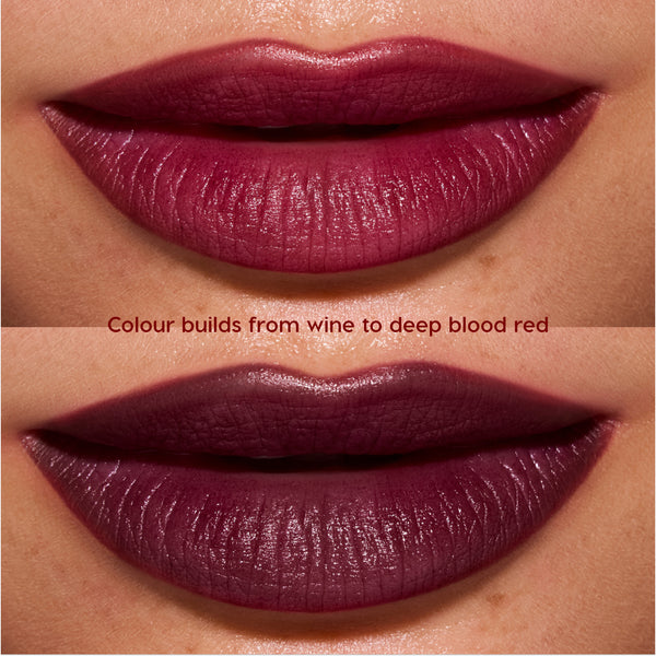 Close-up lips wearing Newborn powder to creme lipstick from the Twilight collection, showing buildable color shifting from rich wine to deep blood-red with a smooth, satin finish on medium skin tone.