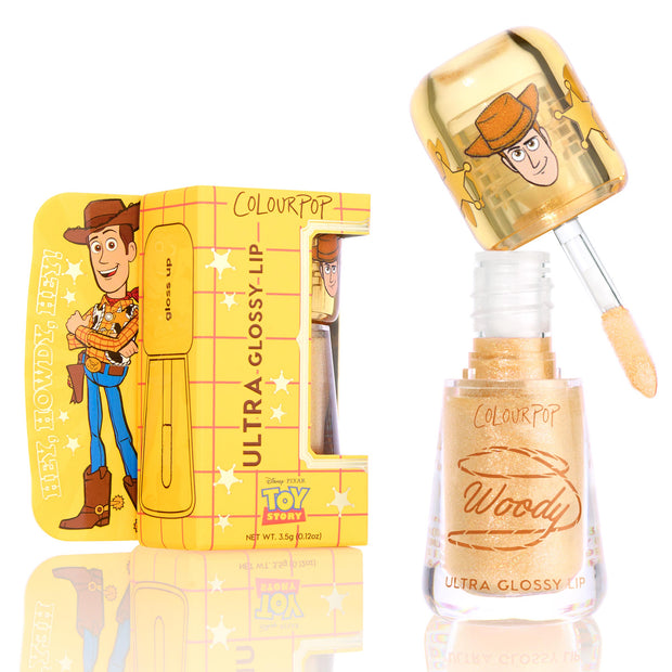 ColourPop Ultra Glossy Lip Favorite Deputy, a warm gold glitter gloss, shown with doe-foot applicator lifted from clear tube; Woody artwork on gold cap and matching yellow Toy Story box, 3.5g/0.12oz.