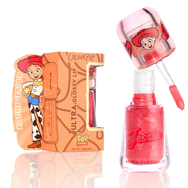 ColourPop Ultra Glossy Lip Yeehaw shows a coral-red, glittery gloss as the doe-foot applicator lifts from the open tube marked Jessie, displayed beside a Disney Pixar Toy Story Jessie–themed box on a bright white background.