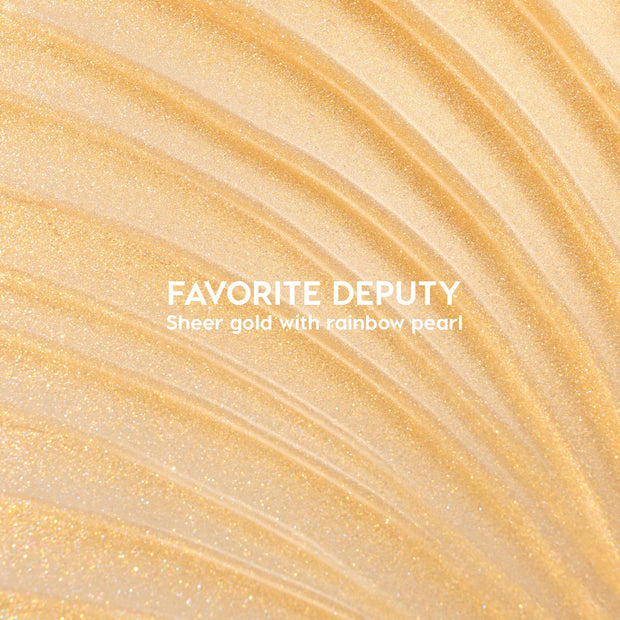 ColourPop Ultra Glossy Lip Favorite Deputy swatch sparkles in sheer gold with rainbow pearl; curved streaks fan across a glossy surface, showcasing a high-shine micro-glitter finish and lightweight, non-opaque coverage.