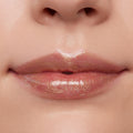 Glossed lips wearing ColourPop Ultra Glossy Lip in Pascal, a sheer clear gloss with gold micro-shimmer, reflecting studio light for a high-shine finish in a close-up beauty swatch.