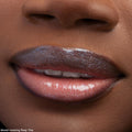 Glossy lips catch the light, wearing ColourPop Ultra Glossy Lip Squad Dreams; the sheer neutral lip gloss delivers a glassy, high-shine finish with fine silver shimmer, shown in an extreme close-up of a model’s mouth and lower nose.