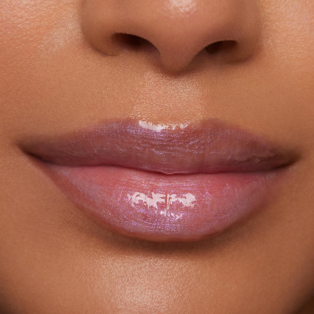 Glossy lips wearing Rapunzel, a sheer pink with violet-blue iridescent shimmer, reflect light in a close-up beauty shot, highlighting the high-shine finish of the ColourPop Ultra Glossy Lip.