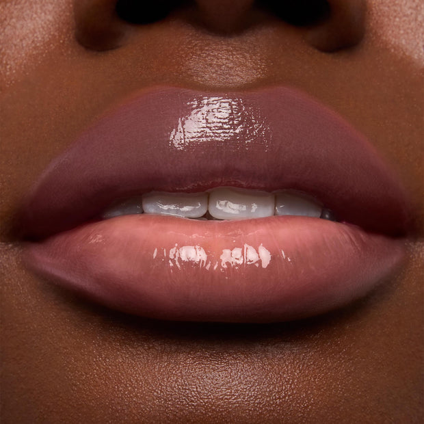 Lips wearing ColourPop Ultra Glossy Lip in Super Sweet, slightly parted and reflecting high-shine gloss, shown in an extreme close-up to highlight the smooth, nude-pink finish and glassy sheen.