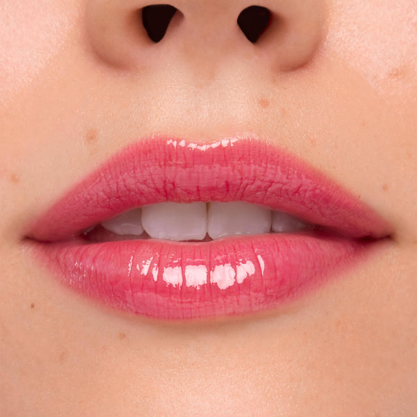 Glossy pink lips wearing ColourPop Ultra Glossy Lip Surfer Vibes in a close-up swatch, showing a high-shine finish with a semi-sheer rosy tint and smooth reflection, framed by natural skin.