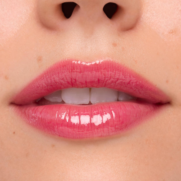 Glossy pink lips wearing ColourPop Ultra Glossy Lip Surfer Vibes in a close-up swatch, showing a high-shine finish with a semi-sheer rosy tint and smooth reflection, framed by natural skin.