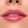 Glossy pink lips wearing ColourPop Ultra Glossy Lip Surfer Vibes in a close-up swatch, showing a high-shine finish with a semi-sheer rosy tint and smooth reflection, framed by natural skin.